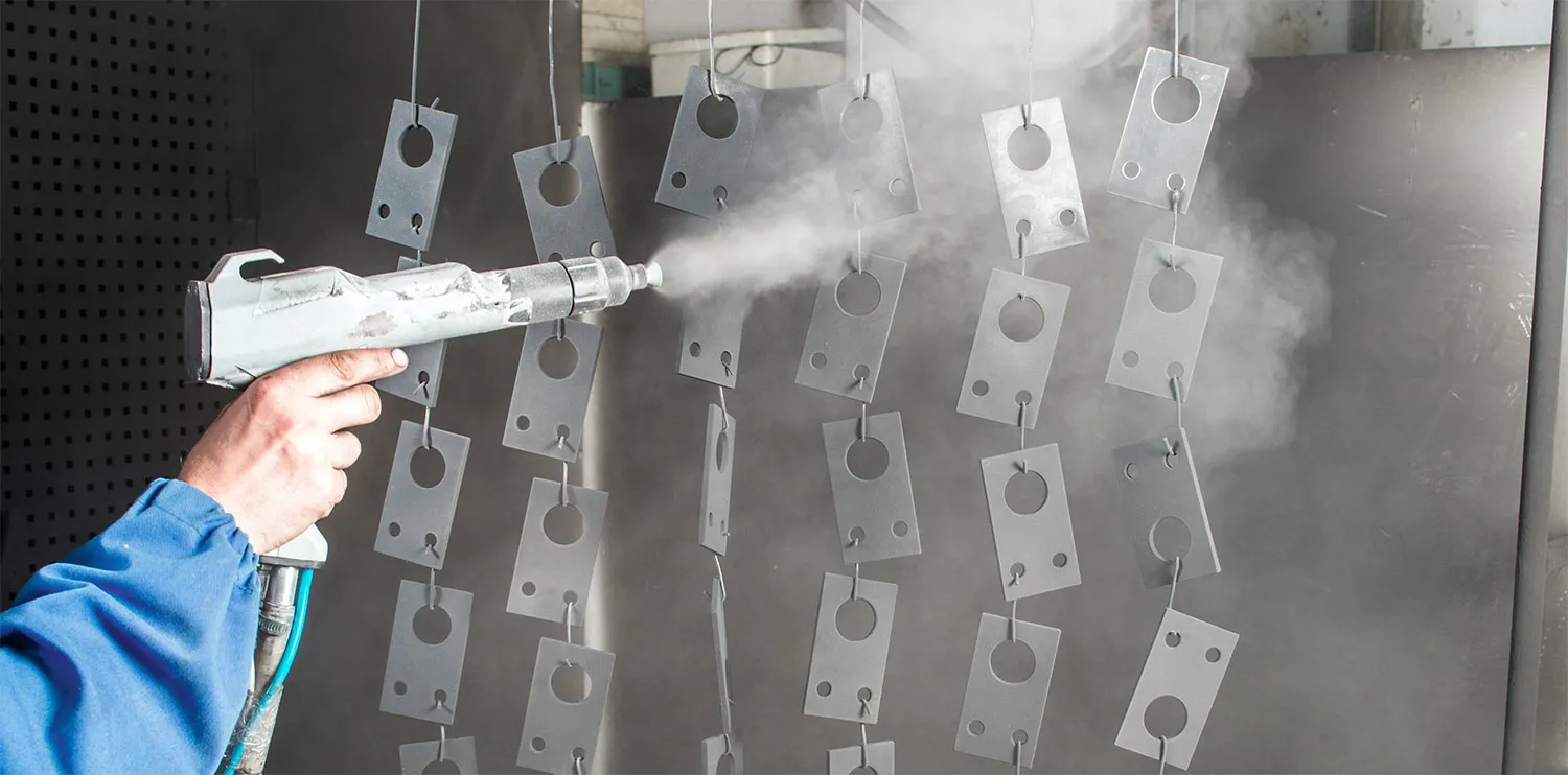 Powder coating being spray-applied to hanging metal parts in a coating booth