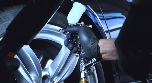 Coating being applied to a car wheel with a spray gun